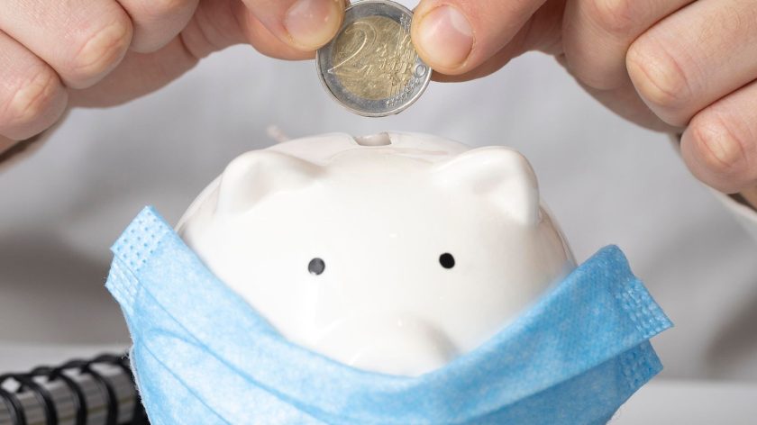 man-inserting-coin-piggy-bank-with-medical-mask.jpg